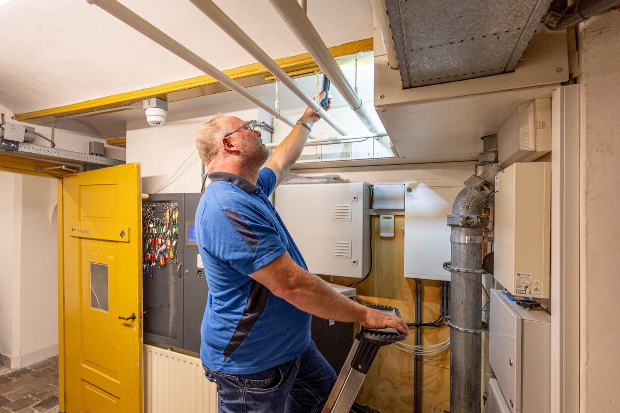 Een inspecteur bekijkt meerdere leidingen in de kelder van Huis Doorn.