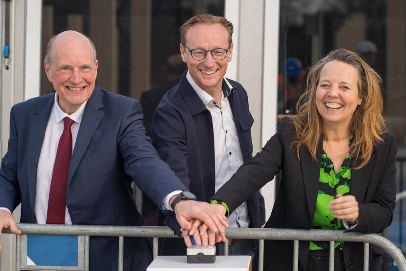 Foto van de onthulling, drie personen drukken op een knop